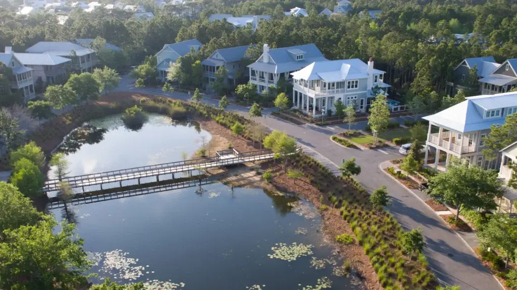 watercolor-fl-lake-district-homes-bridge - Living on 30A Florida WaterColor Florida Lake District homes surrounding a pond with pedestrian bridge